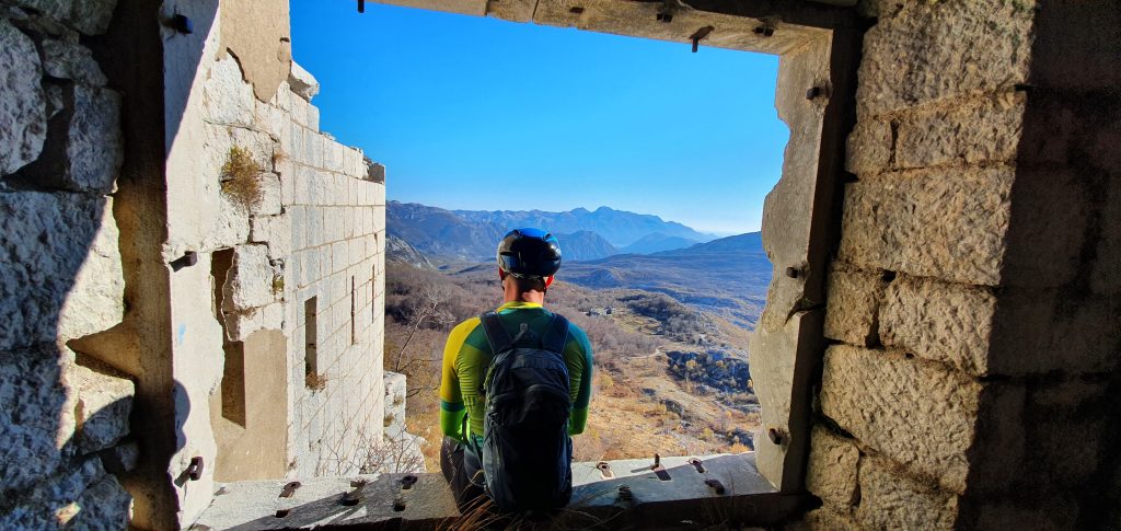 a man sitting on a window ledge looking out to mountains